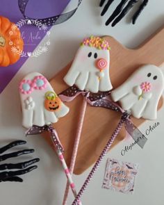 two decorated halloween candy lollipops on a wooden board with black gloves and pumpkins in the background