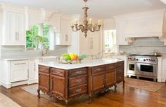 a large kitchen with an island in the middle and chandelier hanging from the ceiling