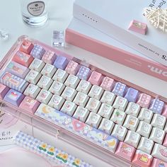 a pink and white keyboard sitting on top of a desk next to a box filled with other items