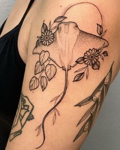 a woman's arm with a tattoo on it that has flowers and a shark