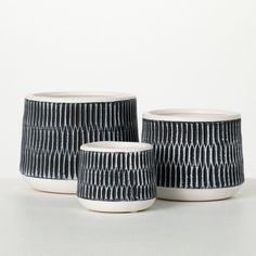 three black and white vases sitting on top of a table