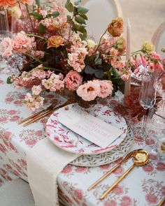 the table is set with pink flowers and place settings