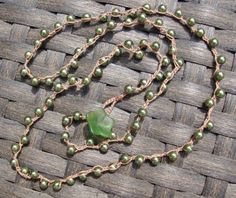 a green beaded necklace on a woven mat