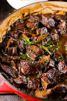 a pot filled with beef and mushrooms on top of a wooden table