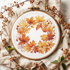 an embroidery project with orange leaves and berries on it, surrounded by white linens