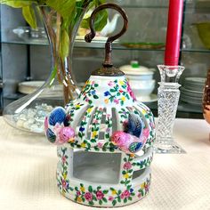 a white table topped with a vase filled with flowers and a birdcage on top of it