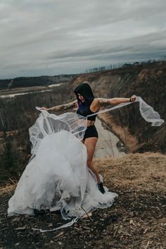 a woman in a black top and white skirt holding a sheer fabric over her body