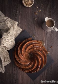 a bundt cake sitting on top of a wooden table next to a cup of coffee