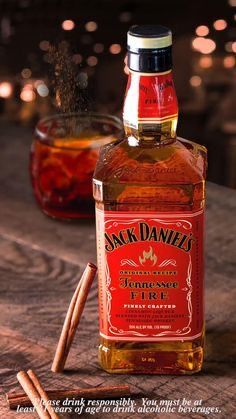 a bottle of jack daniels sitting on top of a table next to two cinnamon sticks