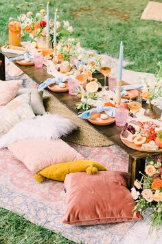 an outdoor bridal shower with flowers and candles on the table, surrounded by pink pillows