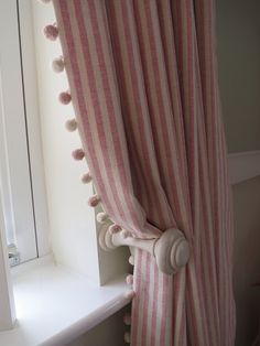 a pink and white striped curtain with pom poms