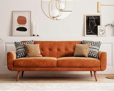 a living room with an orange couch and some pictures on the wall above it, along with potted plants