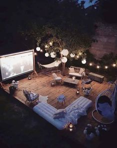 an outdoor movie is set up on the deck at night with string lights strung around it