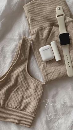 an apple watch, headphones, and other items laid out on top of a bed