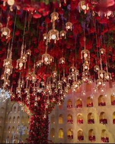 red flowers hanging from the ceiling and chandeliers in front of a white building