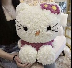 a woman sitting on a couch holding a hello kitty stuffed animal