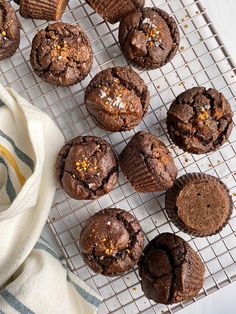 chocolate muffins cooling on a wire rack next to a white and blue towel