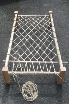 a small white bed frame sitting on top of a black floor next to a power cord