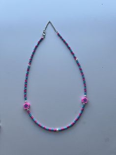 This is a seed bead necklace with a very fun and colorful pattern. It's handmade with a pink and blue pattern and 2 pearls and 2 flower charms.  - We used 2mm beads  - It has an adjustable chain  - The flower charms match the color scheme to make it more aesthetic  - It's very colorful, bright, and pretty  - It's on the girlier side but our shop will have more variety in the future  - The length is 16.5 inches but you can adjust it to your liking Beaded Multicolor Flower Necklace For Beach, Colorful Bead Flower Necklace For Beach, Colorful Beads Flower Necklace For Beach, Adjustable Multicolor Flower Necklace For Beach, Beach Multicolor Flower Necklace, Multicolor Beaded Chain Flower Necklace, Multicolor Flower Necklace With Beaded Chain, Adjustable Beaded Flower Necklace With Round Beads, Pink Bohemian Beaded Necklace With Letter Beads