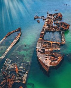 an aerial view of rusted ships in the ocean