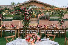 a table set up with flowers and candles for an outdoor wedding reception in the backyard