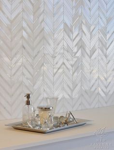 a tray that has some bottles on it next to a wall with white chevron tiles