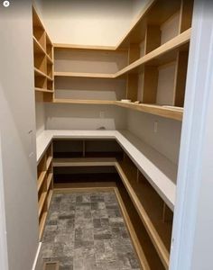 an empty walk in closet with shelves and tile flooring