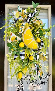 a wreath with lemons and greenery hanging on the front door, decorated with ribbons