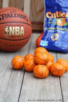 several orange basketballs sitting on top of a wooden table next to a bag of chips