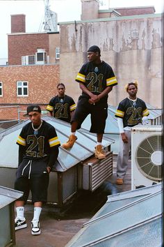 three men in black and yellow uniforms standing on top of a roof