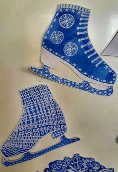 some paper cut outs that are on top of a white table and one has a blue shoe