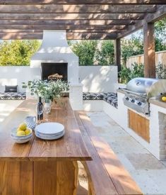 an outdoor kitchen and dining area with wood table, grilling oven, and benches