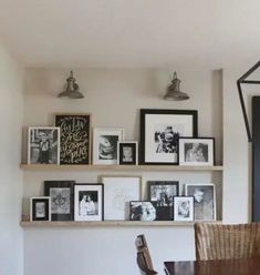 a dining room table with pictures on the wall above it and a lamp hanging from the ceiling