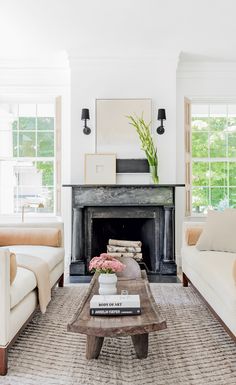 a living room filled with furniture and a fire place in front of a fireplace surrounded by windows