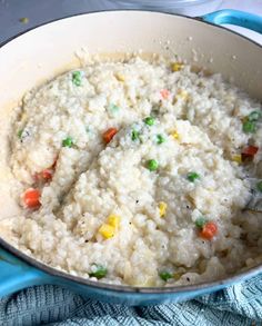 rice with peas and carrots in a pot on a blue towel next to a spoon