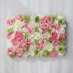 pink and green flowers are arranged on a white surface in the shape of a rectangle