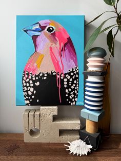 a painting of a colorful bird on a blue background next to some crafting supplies