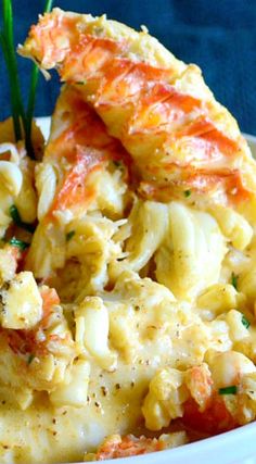 a bowl filled with macaroni and cheese covered in crab meat, garnished with parsley