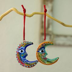 two colorful moon ornaments hanging from a tree branch