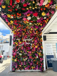 colorful flowers are growing on the side of a building in front of a sign that says,