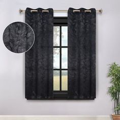 a window with black curtains and a potted plant next to it