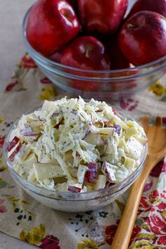 a bowl filled with coleslaw and apples next to a glass bowl full of red apples