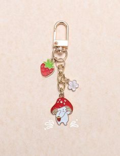 a keychain with a mushroom, strawberry and flower charms on it's side