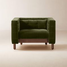 a green couch sitting on top of a white floor next to a wooden frame chair