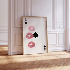 a framed print with four playing cards on the floor next to a white wall and hardwood floor