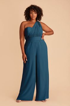 a woman in a blue jumpsuit with her hands on her hips