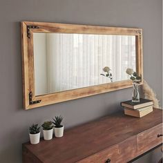 a mirror sitting on top of a wooden dresser next to a vase filled with flowers