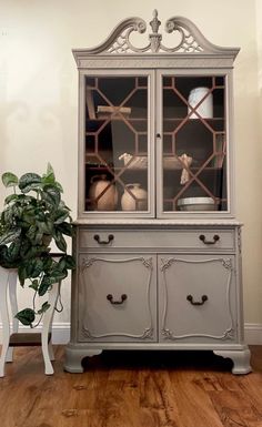 an antique china cabinet with glass doors and drawers in the middle of a wood floored room