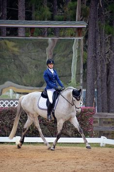 a woman riding on the back of a white horse