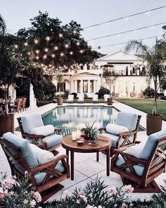 an outdoor patio with chairs and tables next to a pool in the middle of it